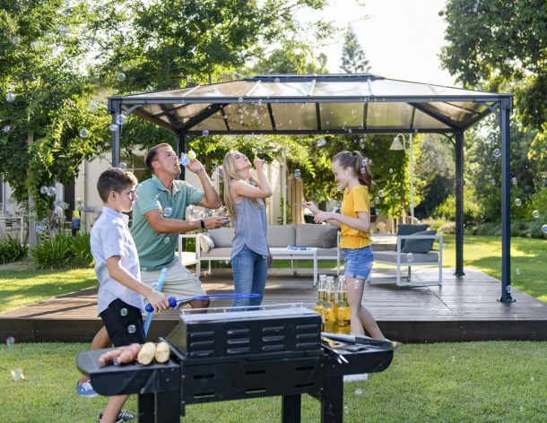 Family Playing With Bubbles In Garden in front of a 10'x14' aluminum gazebo with polycarbonate roof panels