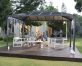 An aluminum gazebo 10'x14' with polycarbonate roof on a deck patio is used by a couple for relaxation