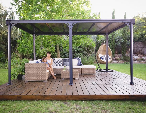 Outdoor gazebo with a flat polycarbonate roof panels on a patio deck with garden furniture