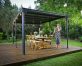 A flat roof gazebo 10' x 14' covers a deck patio with dining furniture and a lady talking on the phone