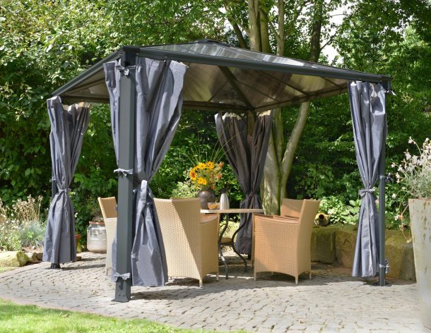 Gray aluminium gazebo with polycarbonate roof panels and privacy curtains on a patio with dining furniture