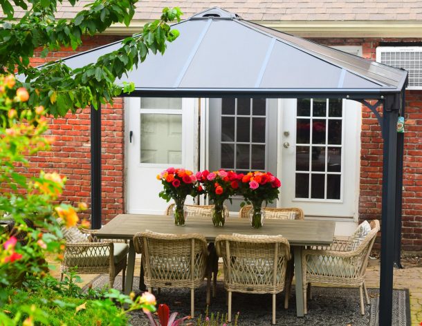 Garden gazebo grey aluminum with polycarbonate roof panels on a deck patio with dining furniture